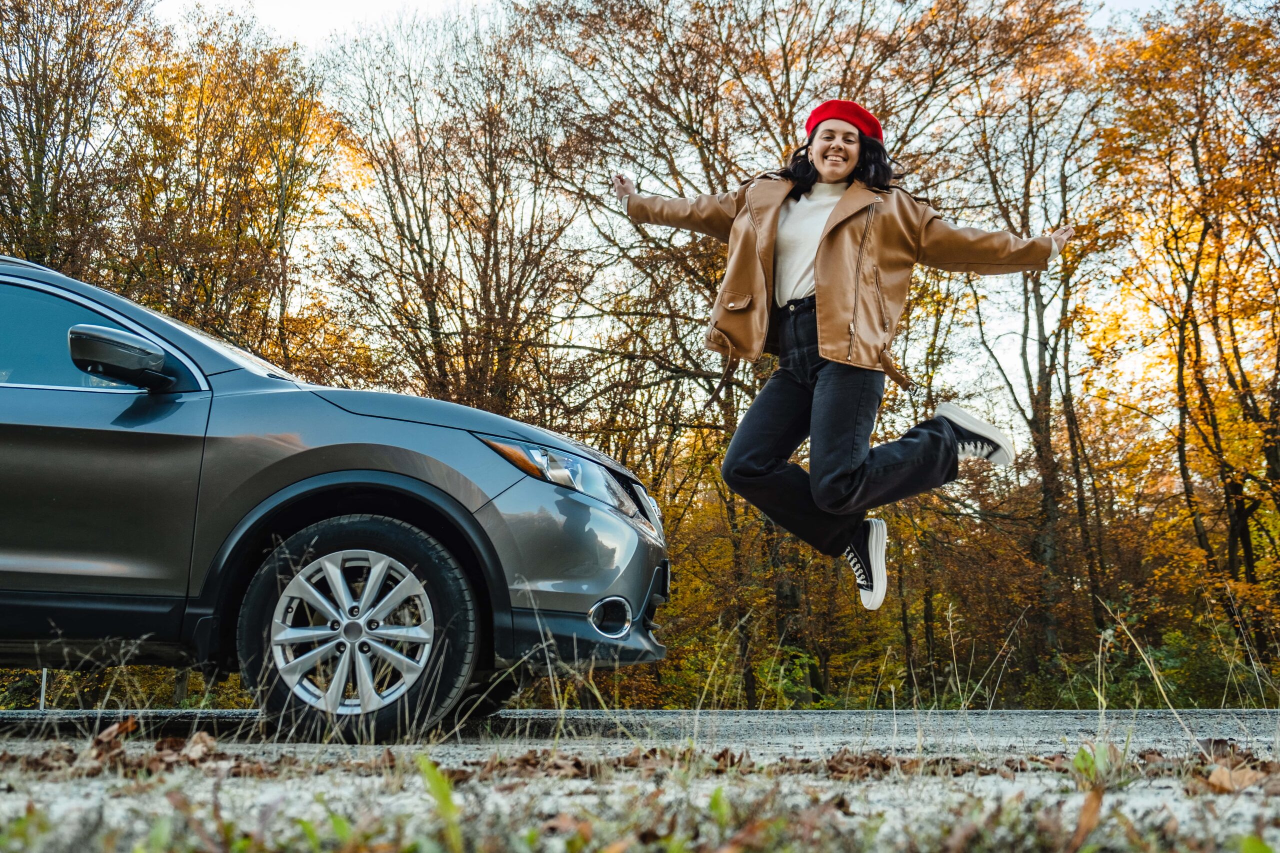happy-smiling-woman-jumping-near-the-car-on-the-ba-2023-11-27-05-33-23-utc-min